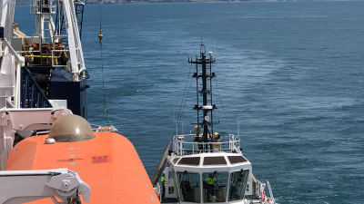 Die Lieferung wird gerade von einem Kran von dem Schlepper an Bord der JR genommen. 