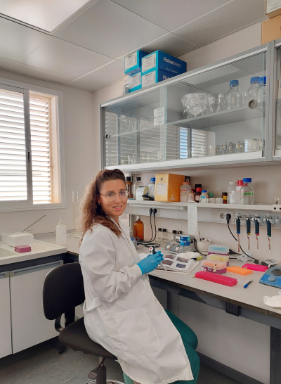 Sofía wearing a lab coat, sitting on a chair in a lab