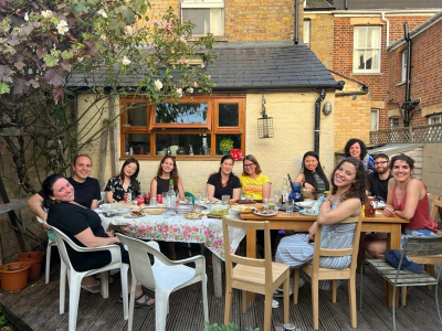 Débora and a group of ten other people sitting outside around a big table with drinks and food; everybody is smiling