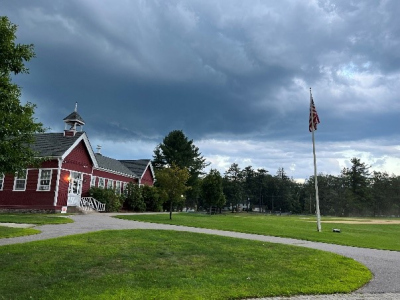 a red wooden building with a green lawn in fron of it