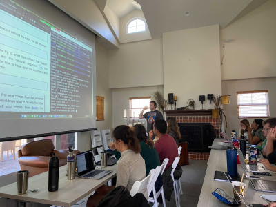 People sitting in front of a screen, one person is explaining something