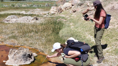 Janina measuring water temperature at a lake while a colleague takes notes