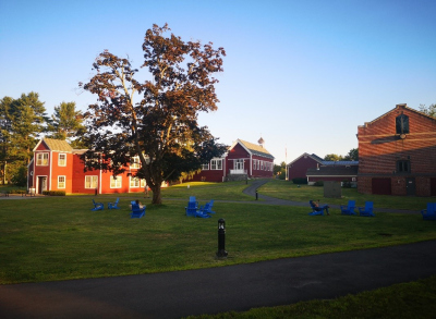 red wooden houses with a lawn and trees in front of them
