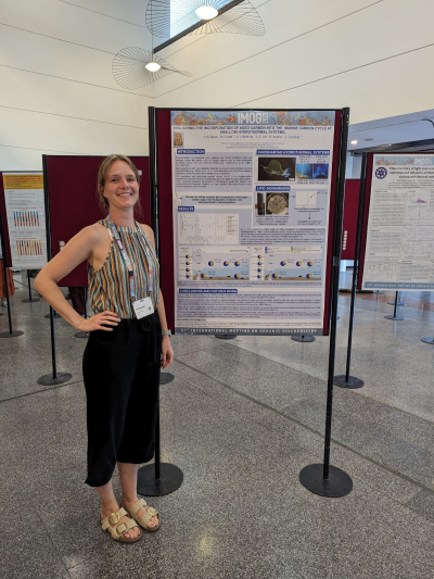 Joelay standing next to her poster