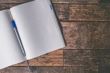 a notebook and a pen laying on a wooden table