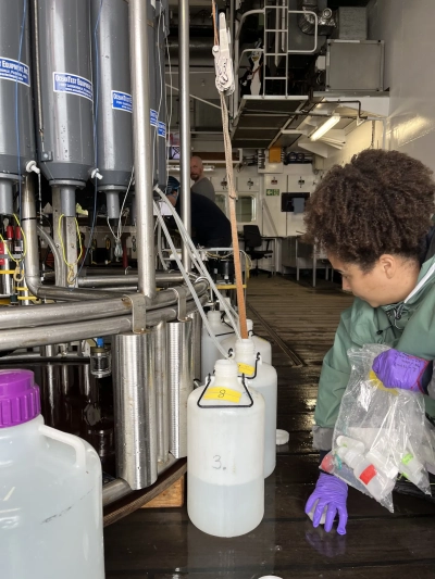 Abbildung zeigt Julia Pamphile Dos Santos sammelt eine Wasserprobe von der CTD in einem Kanister, sodass diese weitertransportiert werden kann.