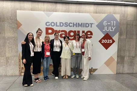 Eva-Maria Meckel with six of her colleagues in front of a Goldschmidt 2025 poster