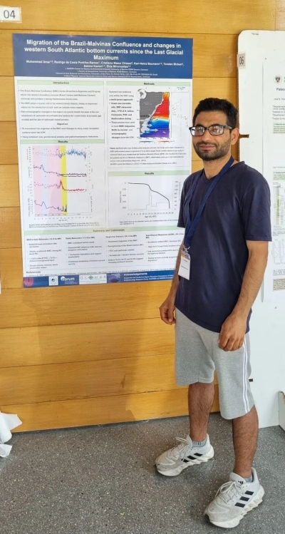 Muhammad Umar standing next to his poster