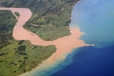 Abbildung zeigt Gesteinsmaterial und Schwebstoffe werden in der Regel in Flüsse und dann ins Meer transportiert. Als Folge entsteht eine Sedimentfahne wie beim Rusizi-Fluss, der in den Tanganjikasee in Burundi mündet. Im Ozean lagern sich die Sedimente Schicht für Schicht ab. Foto: Johanna Ciella, CC BY-SA 4.0 <https://creativecommons.org/licenses/by-sa/4.0>, via Wikimedia Commons