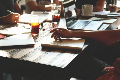 a table with notebooks and laptops and the hands of four people working