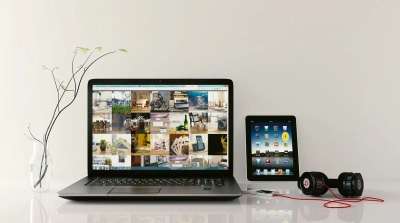 a laptop, tablet and headphones on a table